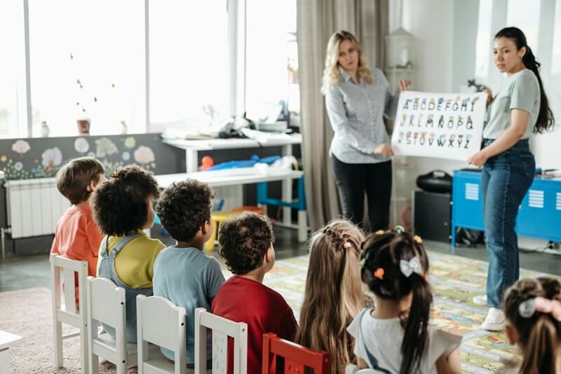 Une enseignante présente l'alphabet à des enfants de maternelle assis en cercle